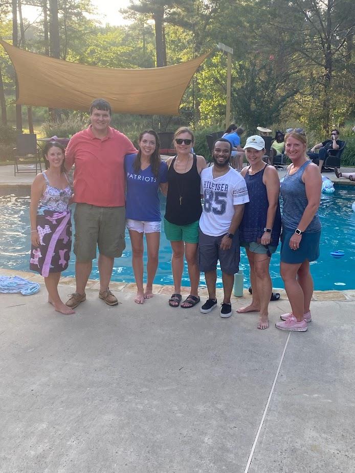 group picture of seven pediatric residents standing in front of outdoor pool